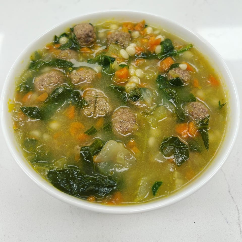 A bowl of Mike's Gourmet Deli and Bagels' hearty soup with meatballs, spinach, carrots, and beans.